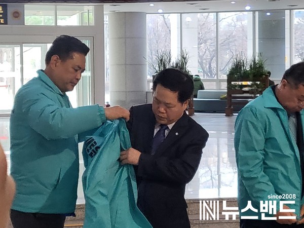 박영순 새로운미래 책임위원이 윤양수 중구의장(가운데)에게 당 색깔의 재킷을 입히고 있다. (사진=이준희 기자)